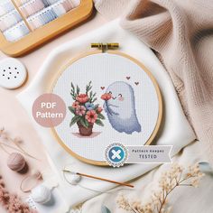 a cross stitch pattern with flowers in a pot and an embroidery kit next to it