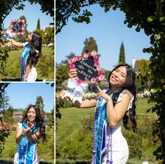 a beautiful young woman holding a sign in front of a lush green park with flowers