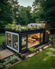 a house made out of shipping containers with plants growing on the roof and patio area