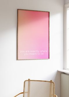 a pink poster hanging on the wall above a chair in a room with white walls