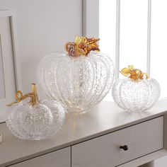 three glass pumpkins sitting on top of a dresser