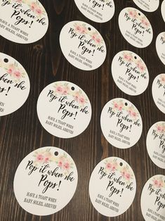 wedding tags with flowers on them sitting on top of a wooden table next to each other