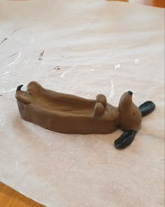 a clay animal laying on top of a piece of paper