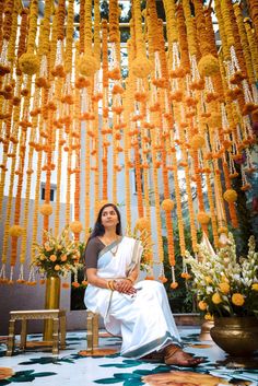 a woman sitting on a chair in front of a bunch of orange and white flowers