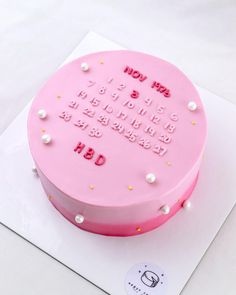 a pink birthday cake on top of a white sheet