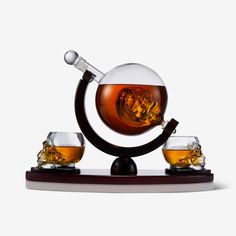 three glasses and a decanter on a stand with an ice ball in it