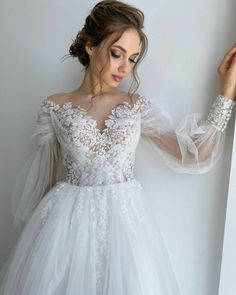 a woman in a white wedding dress leaning against a wall with her hands on the window sill