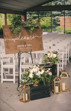 a welcome sign sitting on top of a wooden box next to some flowers and candles