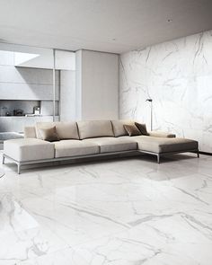 a living room with marble flooring and white furniture in the center, along with a large sectional sofa