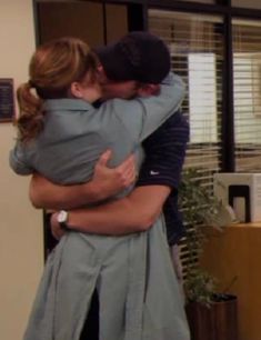 two people hugging each other in an office