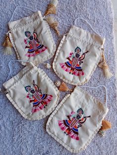 four pieces of embroidered cloth with tassels on them sitting on a blue towel