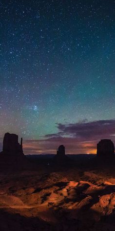 the night sky is lit up with stars above desert land and rock formations in the foreground