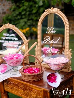 a table topped with baskets filled with flowers next to two mirrors and signs that say the petal pare