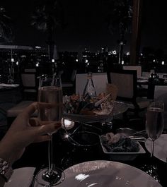 two people toasting champagne at a table with food and drinks in front of them