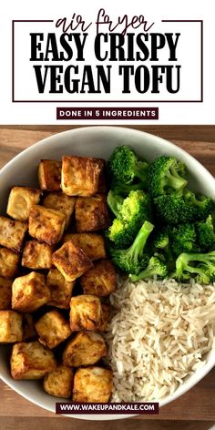 a bowl filled with tofu, rice and broccoli on top of a wooden table