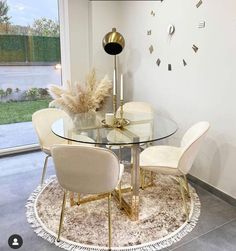 a glass table with four chairs and a clock on the wall in front of it