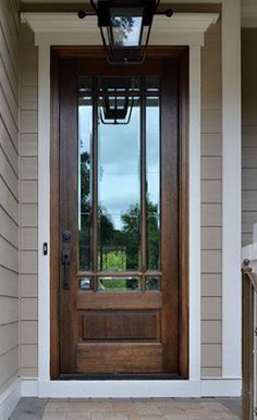 the front door to a house with a lantern on it's post and brick walkway