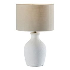 a white ceramic table lamp with a beige shade