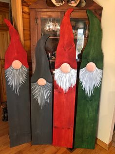 three painted wooden gnomes sitting on top of a hard wood floor next to a clock