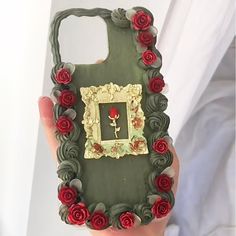 a cell phone case with roses and a picture frame on the back, in someone's hand