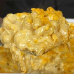 a spoon full of macaroni and cheese being lifted from a casserole dish