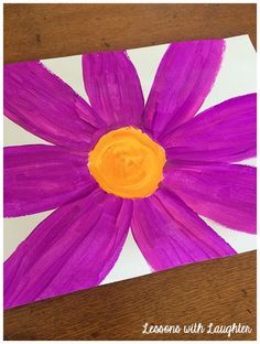 a purple flower with an orange center is on a piece of paper that has been painted