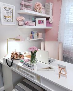 a white desk topped with a laptop computer next to a pink flower filled vase on top of it