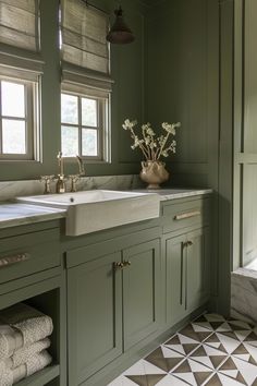 a kitchen with green cabinets and white counter tops, two sinks in front of the window