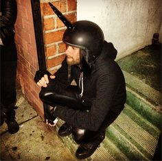 a man sitting on the ground wearing a helmet and holding a knife in his hand