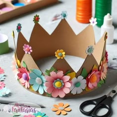 a paper crown sitting on top of a table next to scissors and other crafting supplies