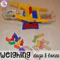 a child's hand is playing with dog bones and toys on the table in front of a toy plane