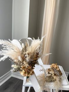 a white chair with some flowers and feathers on it's back legs, sitting in front of a window