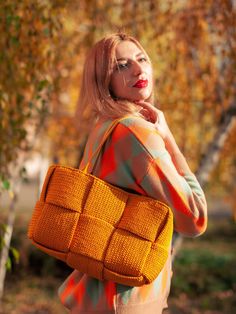 a woman holding a yellow purse in front of her face and looking off to the side