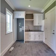 an empty kitchen with tile flooring and white cabinets