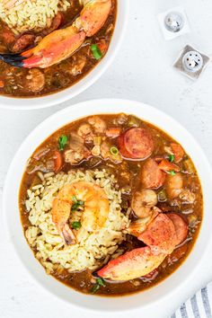 two bowls filled with shrimp and rice on top of a white tablecloth next to silverware