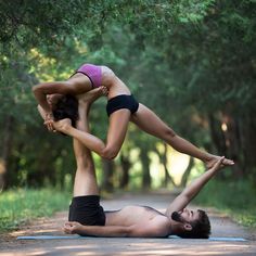 a man and woman doing yoga in the middle of a road with trees behind them