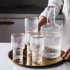 a gold tray with four glass vases sitting on top of it next to another set of glasses