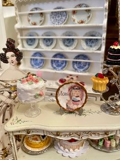 there are many plates and cakes on the shelf in this room, including one with a woman's face