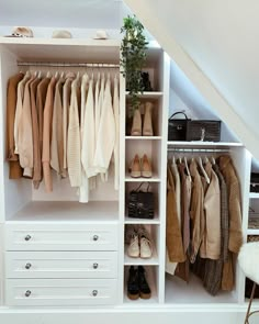 an organized closet with shoes, sweaters and handbags on shelves under the stairs