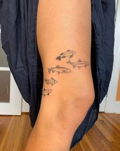 a woman's leg with fish tattoos on it