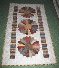 a quilted table runner with two large flowers on the front and one small flower on the back