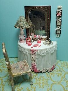 a doll's room with a table and chair next to a mirror on the wall