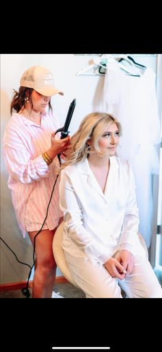 a woman is getting her hair done by another woman in a white shirt and hat