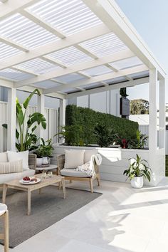 an outdoor living area with white furniture and plants