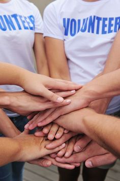 a group of people holding hands together in the middle of a circle with volunteer t - shirts on