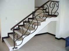 a set of stairs with wrought iron handrails in an empty room next to a blue chair