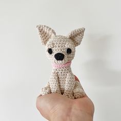 a small crocheted dog sitting in the palm of someone's hand