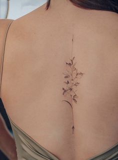 the back of a woman's shoulder with a flower tattoo on it