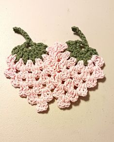 a crocheted piece of fruit hanging on the wall with green and pink trim