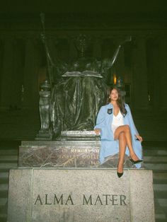 a woman sitting on top of a bench next to a statue